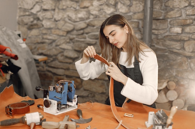 Foto gratuita mujer joven que trabaja en su espacio de trabajo mujer que lleva un delantal y que hace un fondo de textura de piedra oscura de grounge del cinturón