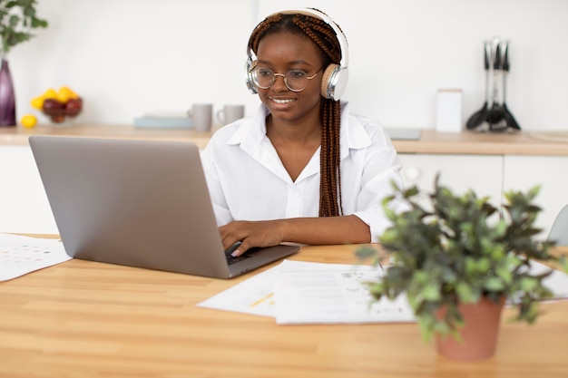 Mujer joven que trabaja con sus auriculares en