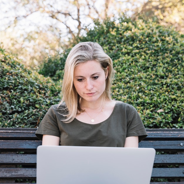 Mujer joven que usa la computadora portátil en banco