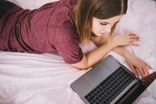 Foto gratuita mujer joven que usa la computadora portátil en cama