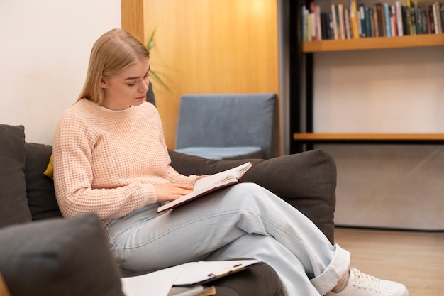 Mujer joven que usa documentos para estudiar en una biblioteca