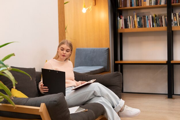 Mujer joven que usa documentos para estudiar en una biblioteca