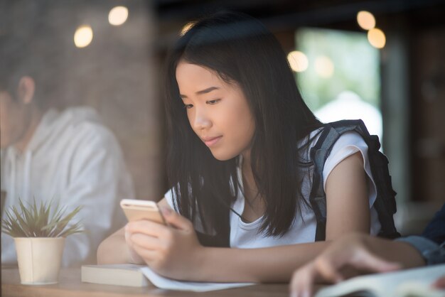 Mujer joven que usa y que mira el smartphone con la sensación feliz