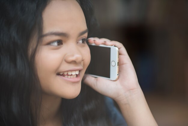 Foto gratuita mujer joven que usa y que mira el smartphone con la sensación feliz