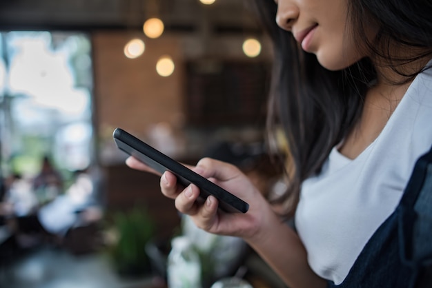 Mujer joven que usa y que mira el smartphone con la sensación feliz