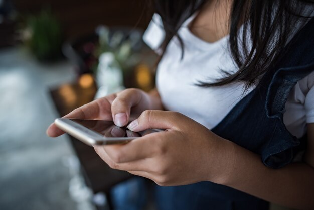 Mujer joven que usa y que mira el smartphone con la sensación feliz