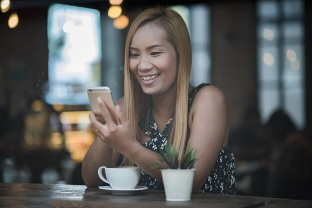 Mujer joven que usa y que mira el smartphone con la sensación feliz