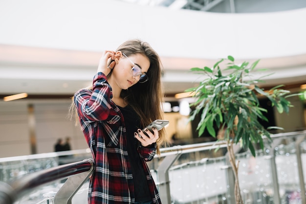 Foto gratuita mujer joven que usa smartphone en centro comercial
