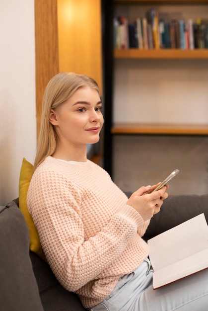 Foto gratuita mujer joven que usa su teléfono inteligente en una biblioteca