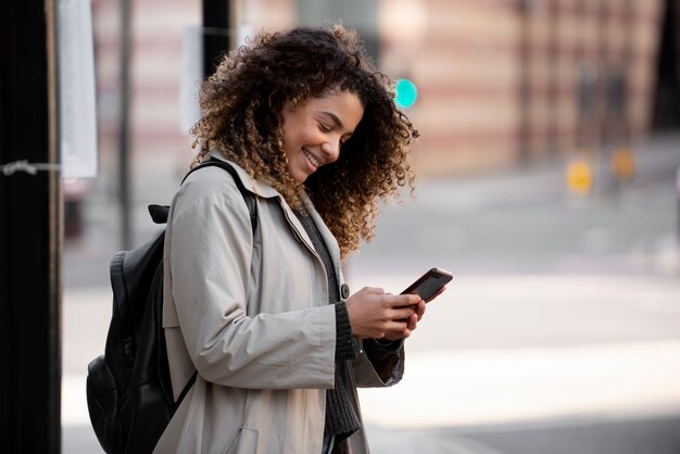 Mujer joven que usa su teléfono inteligente en la ciudad