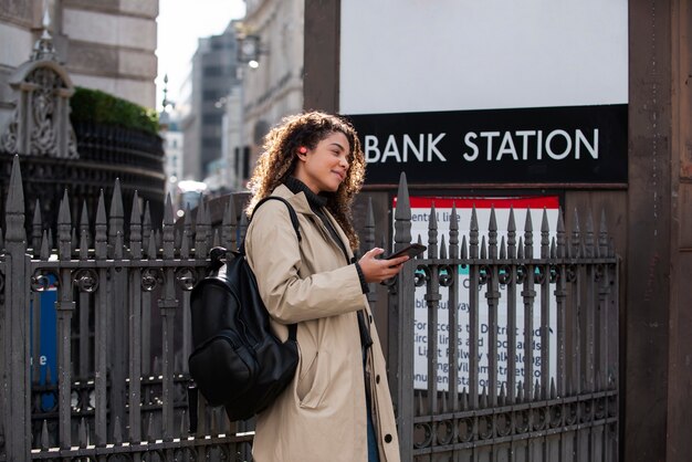 Mujer joven que usa su teléfono inteligente en la ciudad