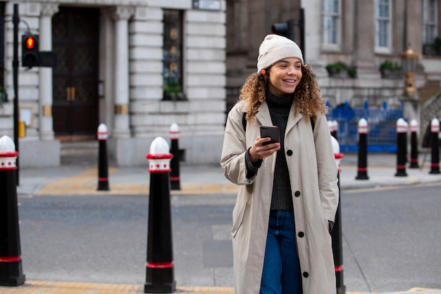 Mujer joven que usa su teléfono inteligente en la ciudad