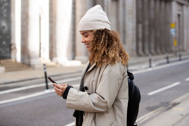 Mujer joven que usa su teléfono inteligente en la ciudad