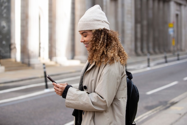 Mujer joven que usa su teléfono inteligente en la ciudad