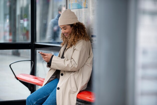 Mujer joven que usa su teléfono inteligente en la ciudad