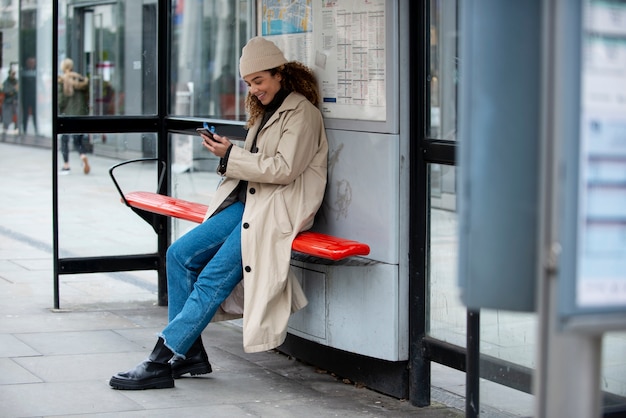 Mujer joven que usa su teléfono inteligente en la ciudad
