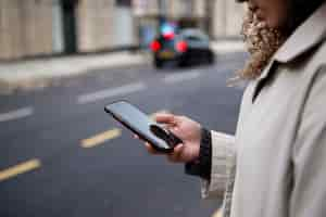 Foto gratuita mujer joven que usa su teléfono inteligente en la ciudad