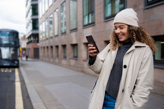 Mujer joven que usa su teléfono inteligente en la ciudad