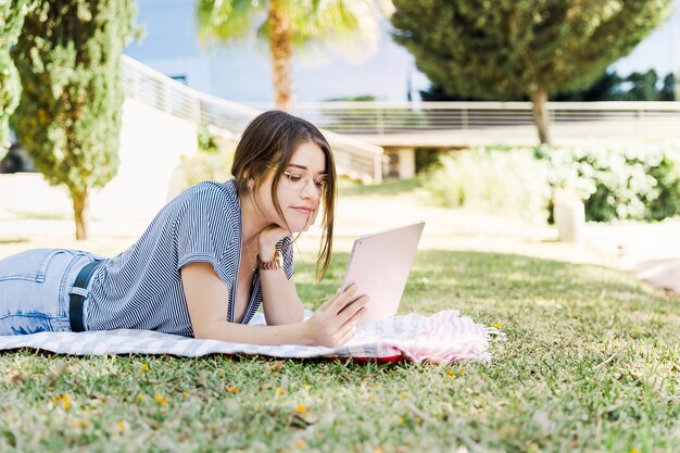 Mujer joven que usa la tableta en el parque