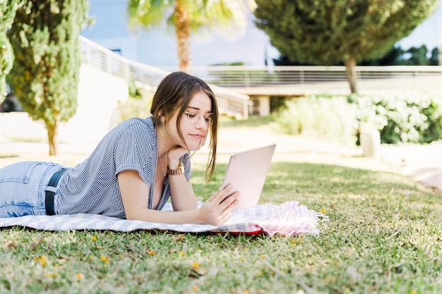 Mujer joven que usa la tableta en el parque