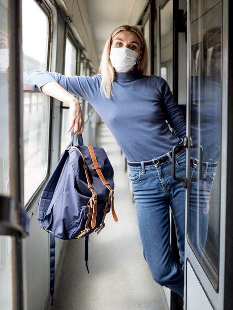 Mujer joven que viaja en tren con máscara