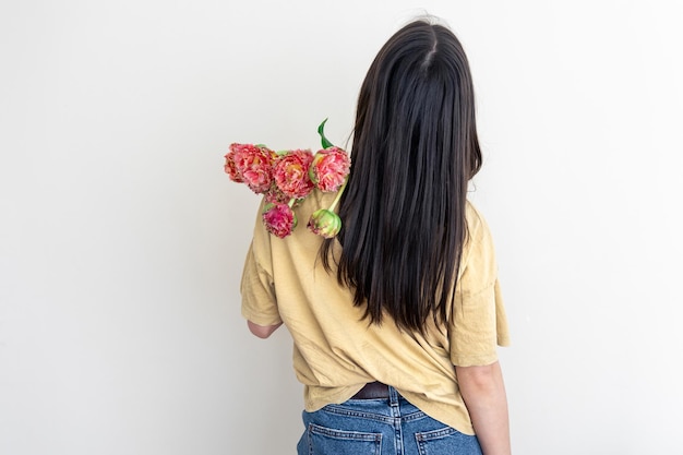 Una mujer joven con un ramo de flores sobre un fondo blanco.