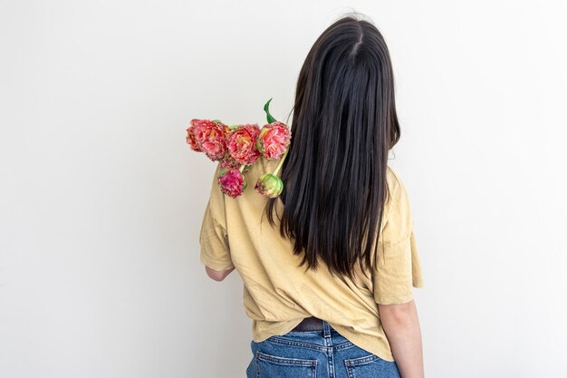 Una mujer joven con un ramo de flores sobre un fondo blanco.