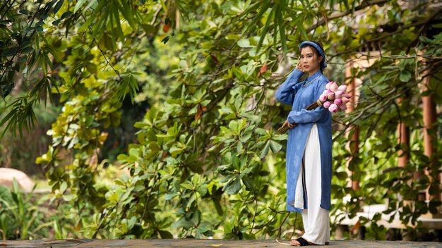 Mujer joven con ramo de flores vistiendo traje ao dai