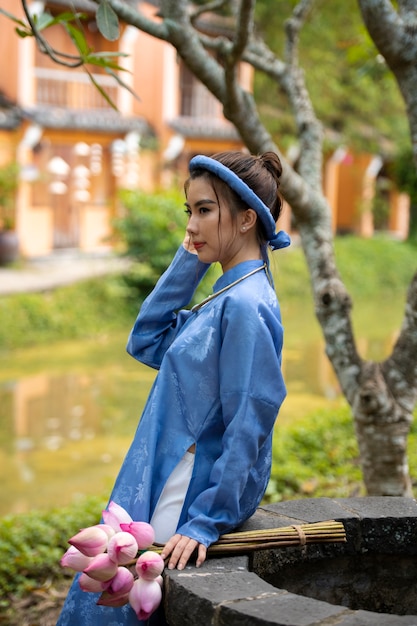 Mujer joven con ramo de flores vistiendo traje ao dai