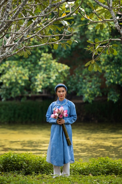 Mujer joven con ramo de flores vistiendo traje ao dai