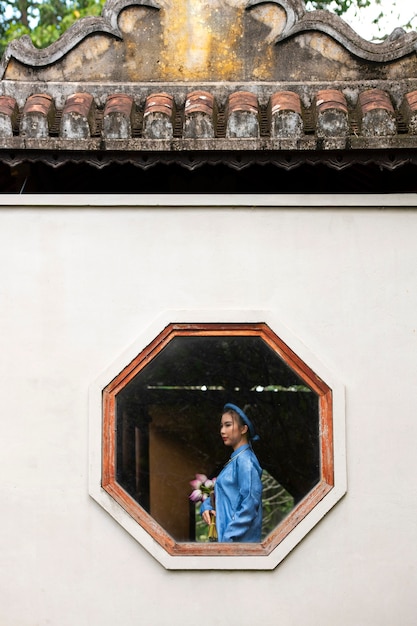 Foto gratuita mujer joven con ramo de flores vistiendo traje ao dai