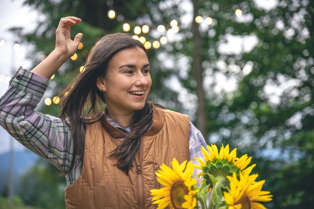 Una mujer joven con un ramo de girasoles sobre un fondo borroso en la naturaleza