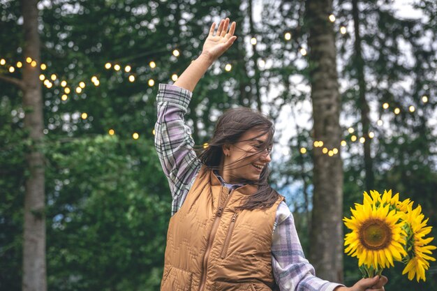 Una mujer joven con un ramo de girasoles sobre un fondo borroso en la naturaleza