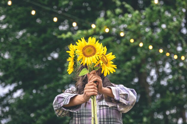 Una mujer joven con un ramo de girasoles sobre un fondo borroso en la naturaleza