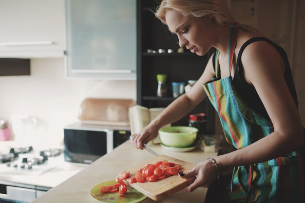 Mujer joven, rebanar, tomates