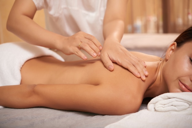 Mujer joven recibiendo masaje de espalda en el salón de spa