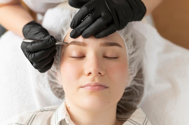 Mujer joven recibiendo un tratamiento de cejas en el salón de belleza