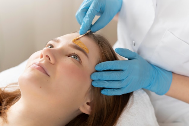 Mujer joven recibiendo un tratamiento de cejas en el salón de belleza