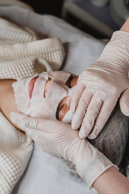 Mujer joven recibiendo un tratamiento con mascarilla para la piel en el centro de bienestar