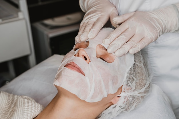 Mujer joven recibiendo un tratamiento de mascarilla para la piel en el spa