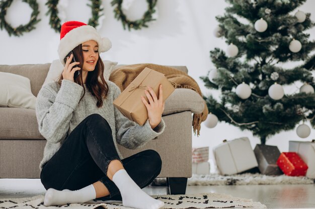 Mujer joven con regalos de navidad por el árbol de navidad