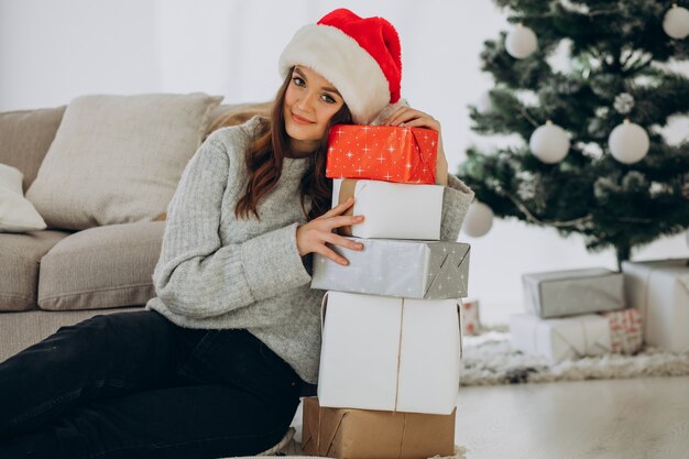 Mujer joven con regalos de navidad por el árbol de navidad