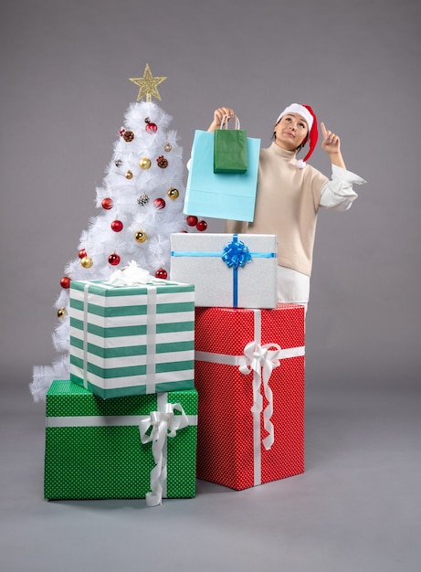 mujer joven con regalos navideños en gris