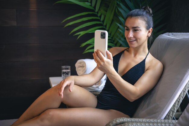 Una mujer joven se relaja en un complejo de spa y usa un teléfono inteligente