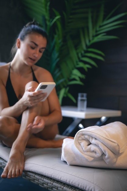 Una mujer joven se relaja en un complejo de spa y usa un teléfono inteligente