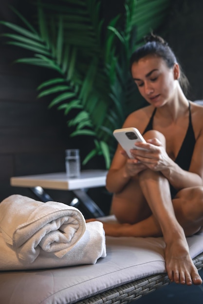 Una mujer joven se relaja en un complejo de spa y usa un teléfono inteligente