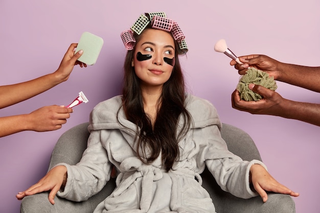 Foto gratuita mujer joven relajada en bata de baño suave, usa parches cosméticos debajo de los ojos