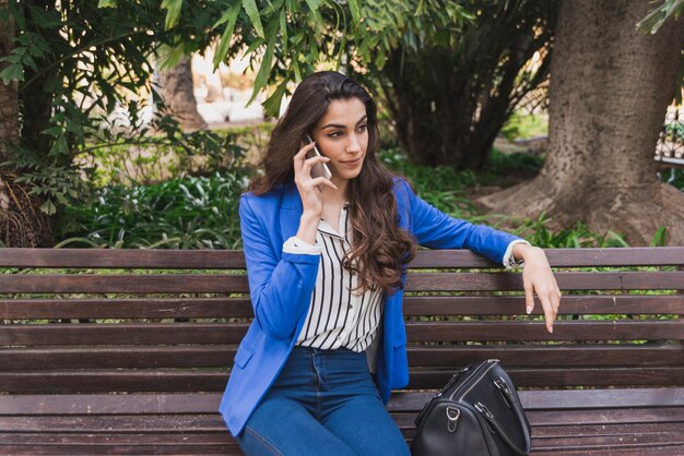 Mujer joven relajada hablando por teléfono en el parque