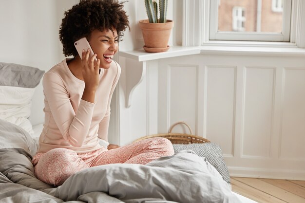 Mujer joven relajada con su teléfono posando en casa