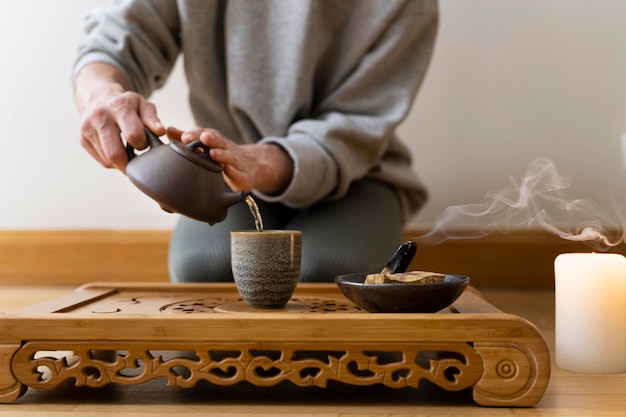 Mujer joven relajándose en casa con té y salvia ardiente